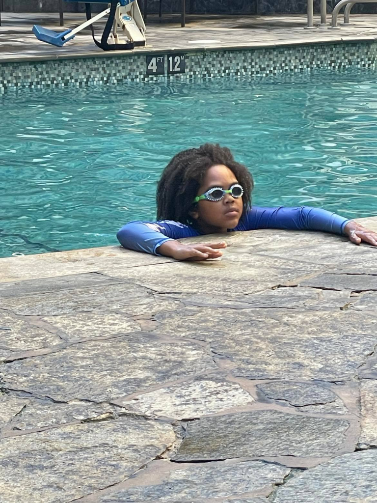 Boy with curly hair and goggles looking out of the pool