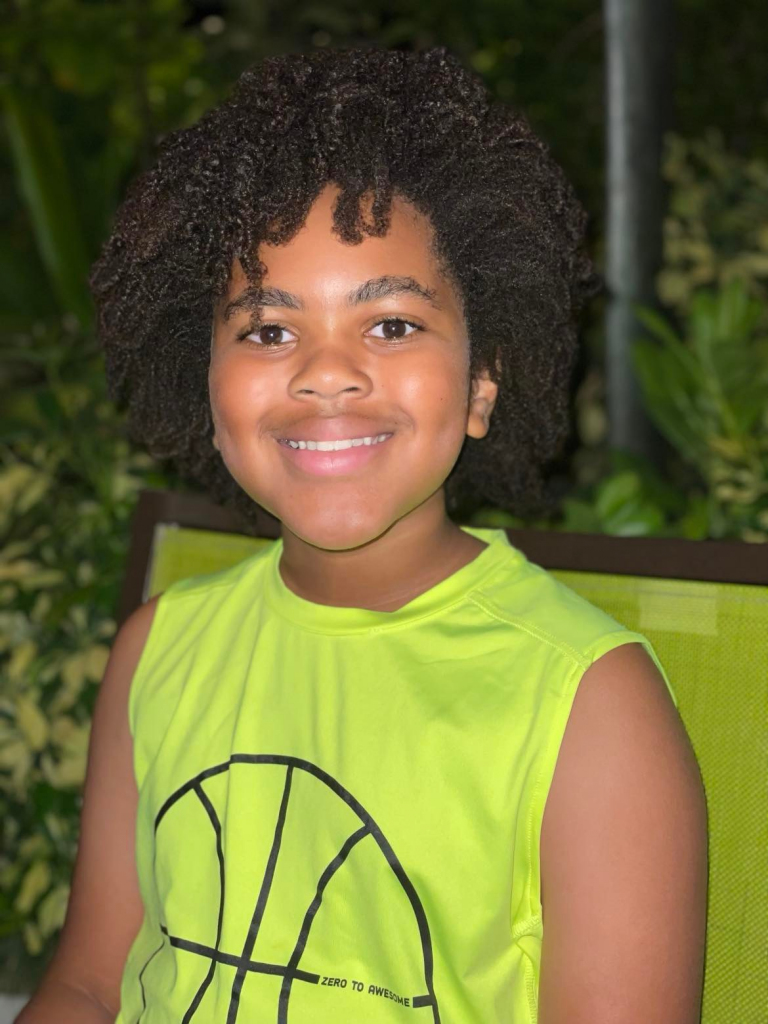 Boy with Curly hair smiling with bright green shirt